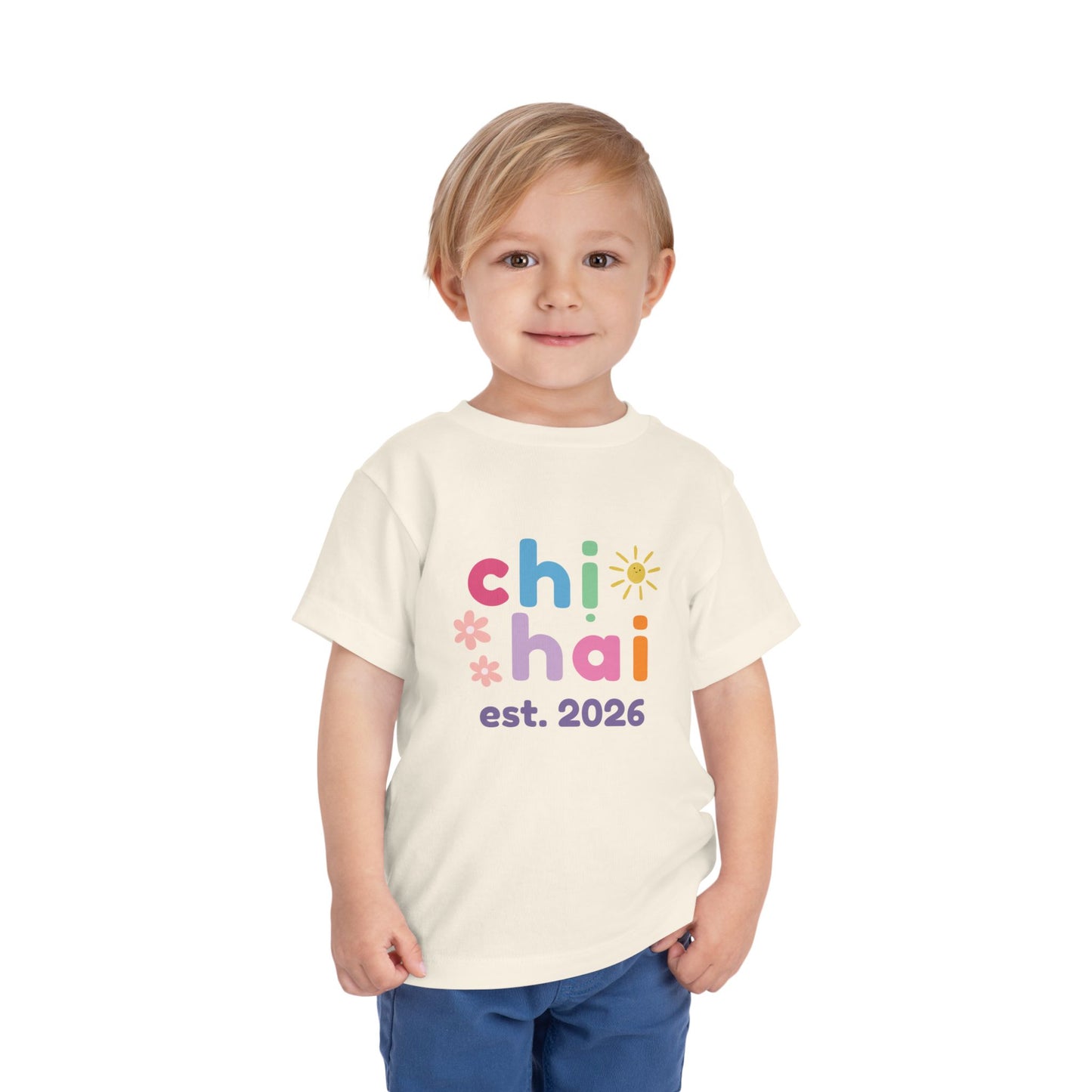 Child wearing a natural color t-shirt with colorful text chi hai est. 2026