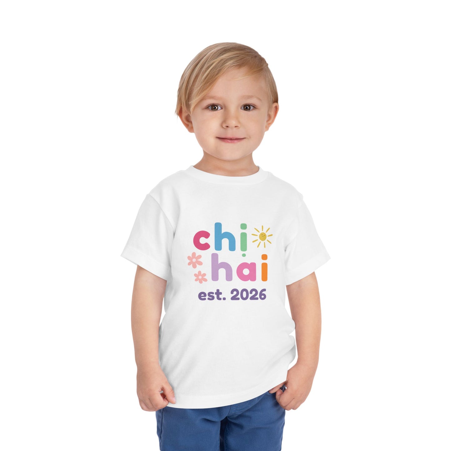 Child wearing a white t-shirt with colorful text chi hai est. 2026