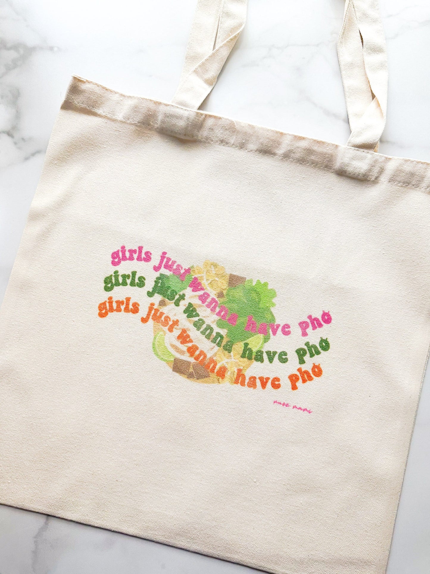 Canvas tote bag with the phrase 'girls just wanna have pho' printed in colorful text on the front.