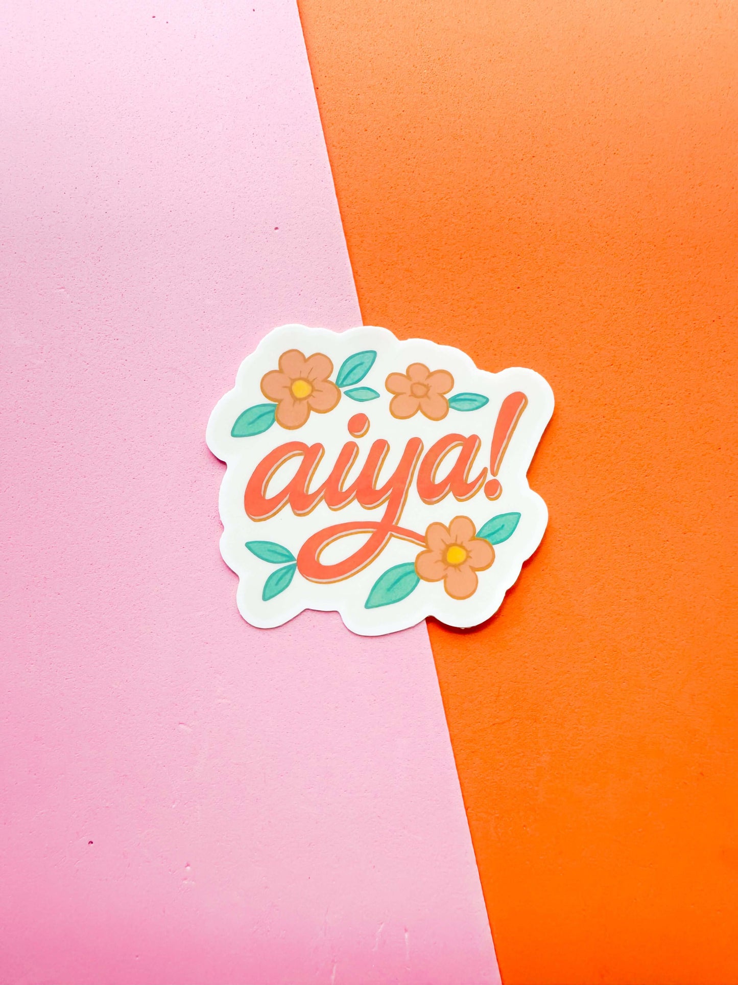 A matte premium vinyl sticker with the word 'aiya' written in stylized lettering, surrounded by floral designs