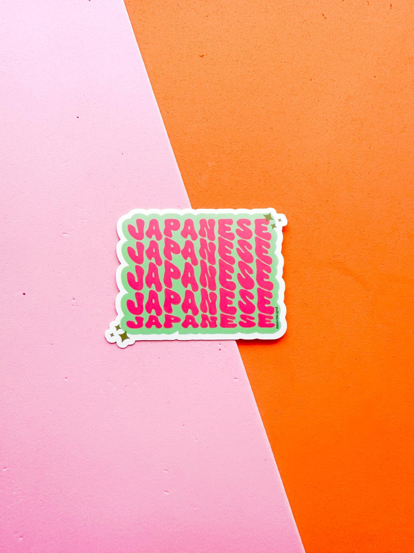 A vinyl sticker with Japanese text in pink on a green background