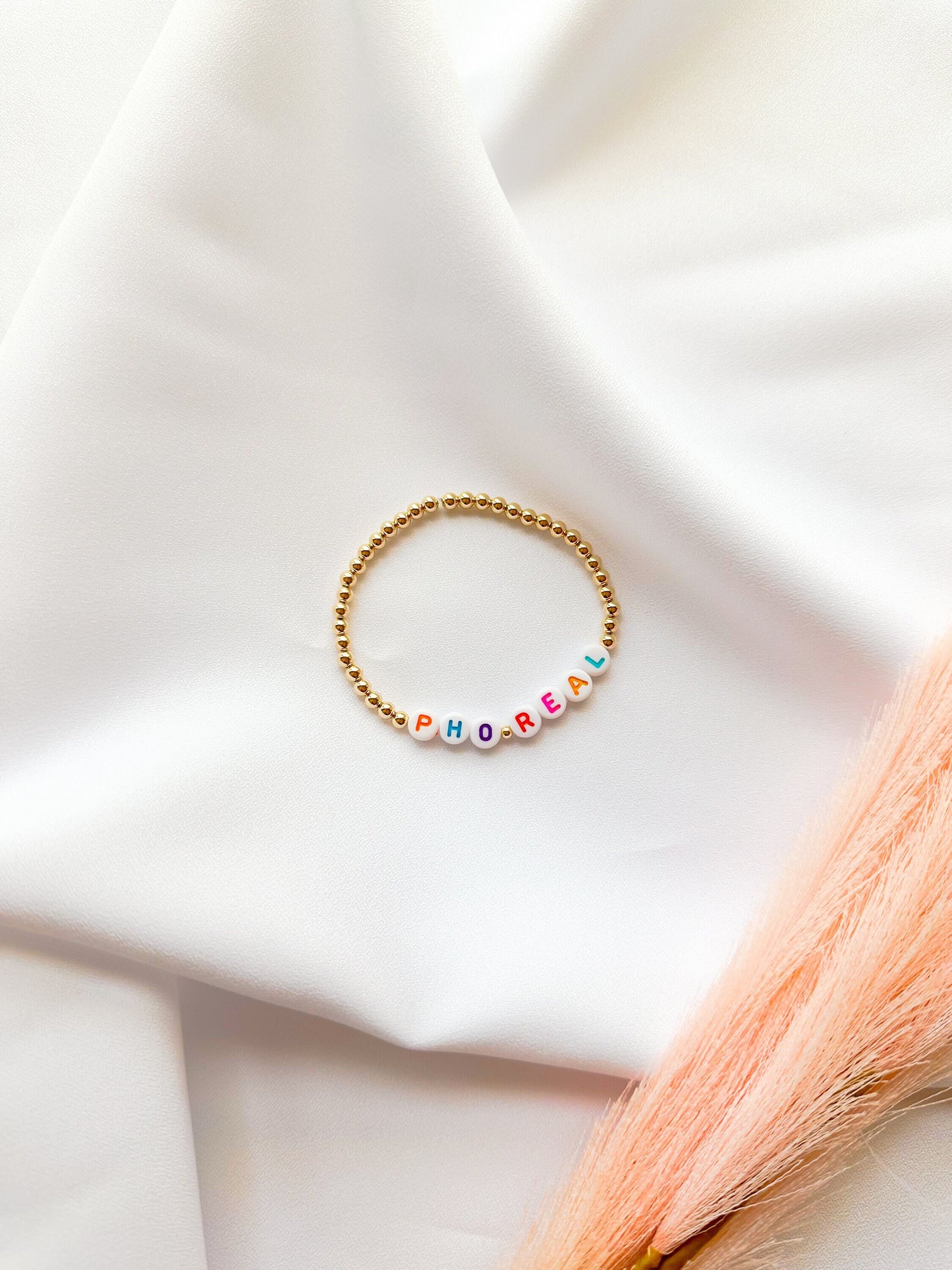 A gold-filled beaded bracelet with the phrase 'PHO REAL'