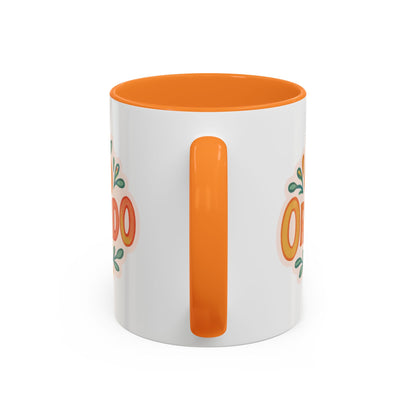 white ceramic mug with 'Orlando' written in orange lettering, accompanied by a graphic of orange and green leaves. The mug has an orange interior and handle.