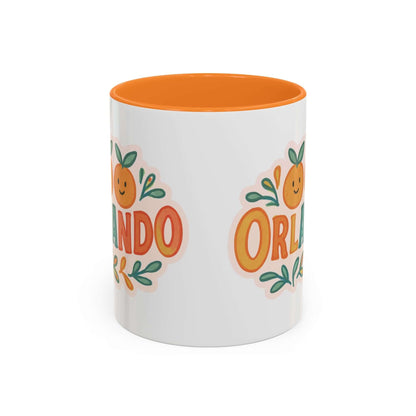 white ceramic mug with 'Orlando' written in orange lettering, accompanied by a graphic of orange and green leaves. The mug has a pink interior and handle.