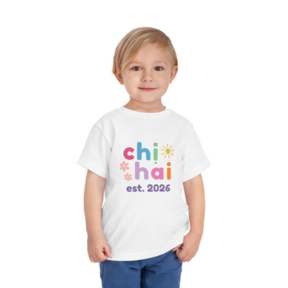 Child wearing a white t-shirt with colorful text chi hai est. 2026