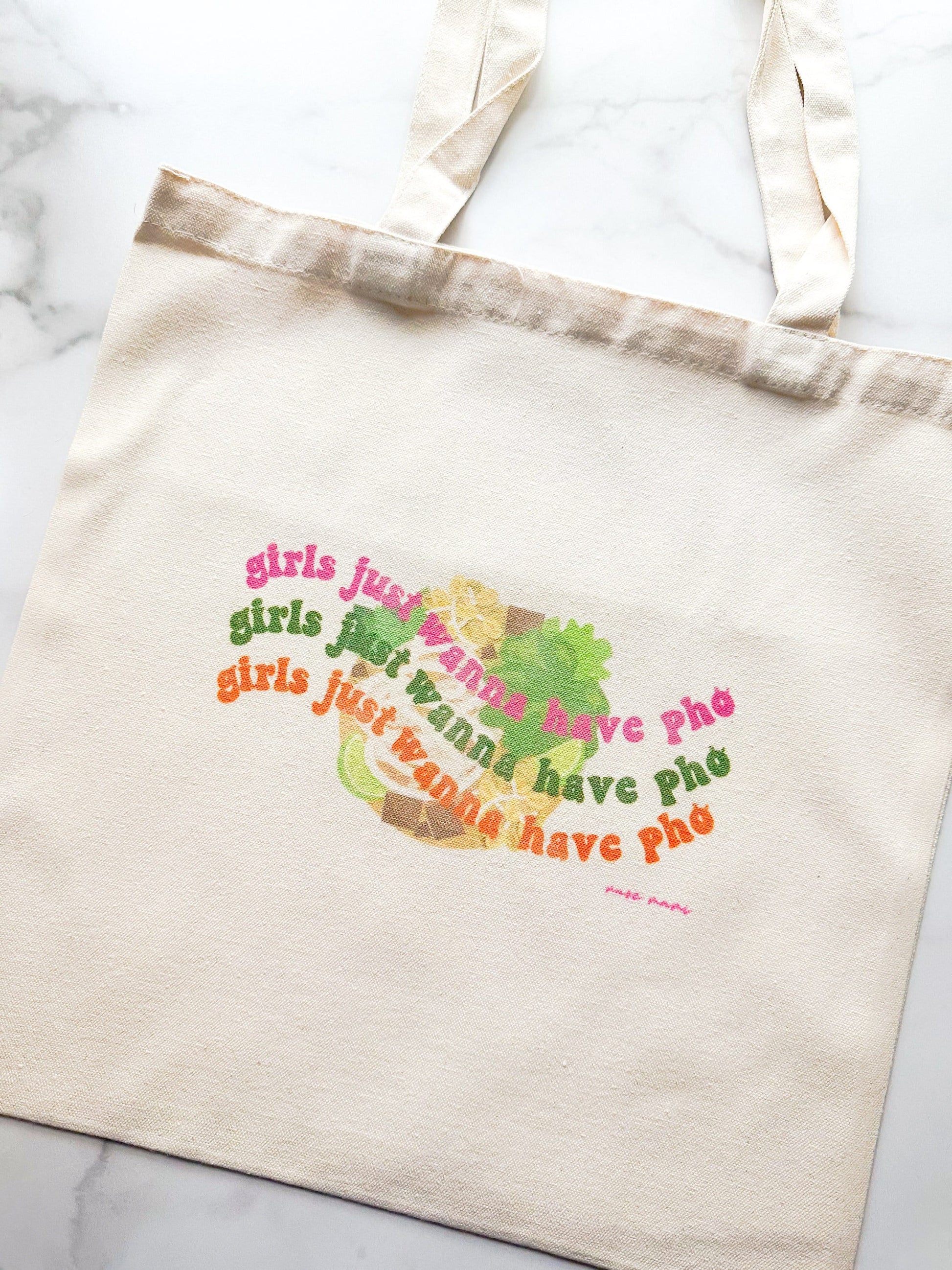 Canvas tote bag with the phrase 'girls just wanna have pho' printed in colorful text on the front.