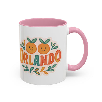 white ceramic mug with 'Orlando' written in orange lettering, accompanied by a graphic of orange and green leaves. The mug has a pink interior and handle.