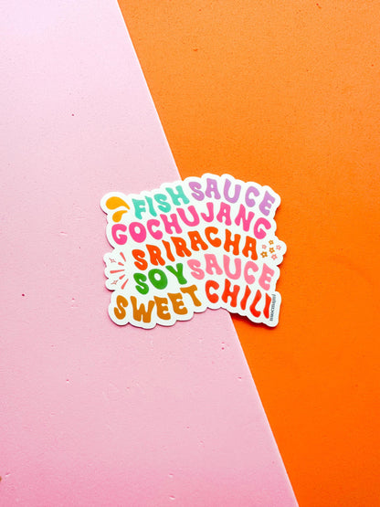 A colorful vinyl sticker with the text 'FISH SAUCE, GOCHUJANG, SOY SAUCE, SRIRACHA, SWEET CHILI' arranged in a playful font 