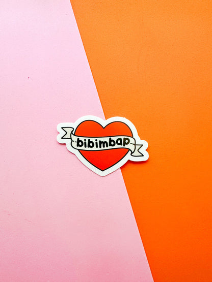 A vinyl sticker with a red heart and the text 'bibimbap' written inside 