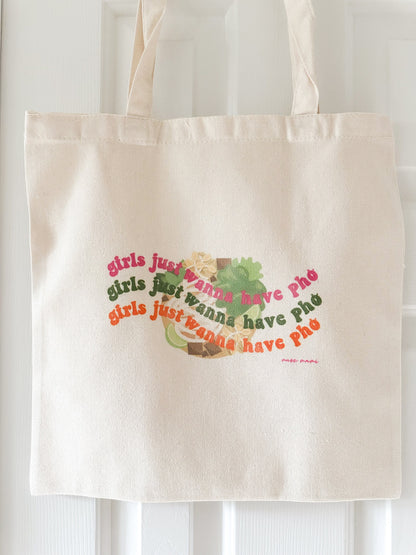 Canvas tote bag with the phrase 'girls just wanna have pho' printed in colorful text on the front.