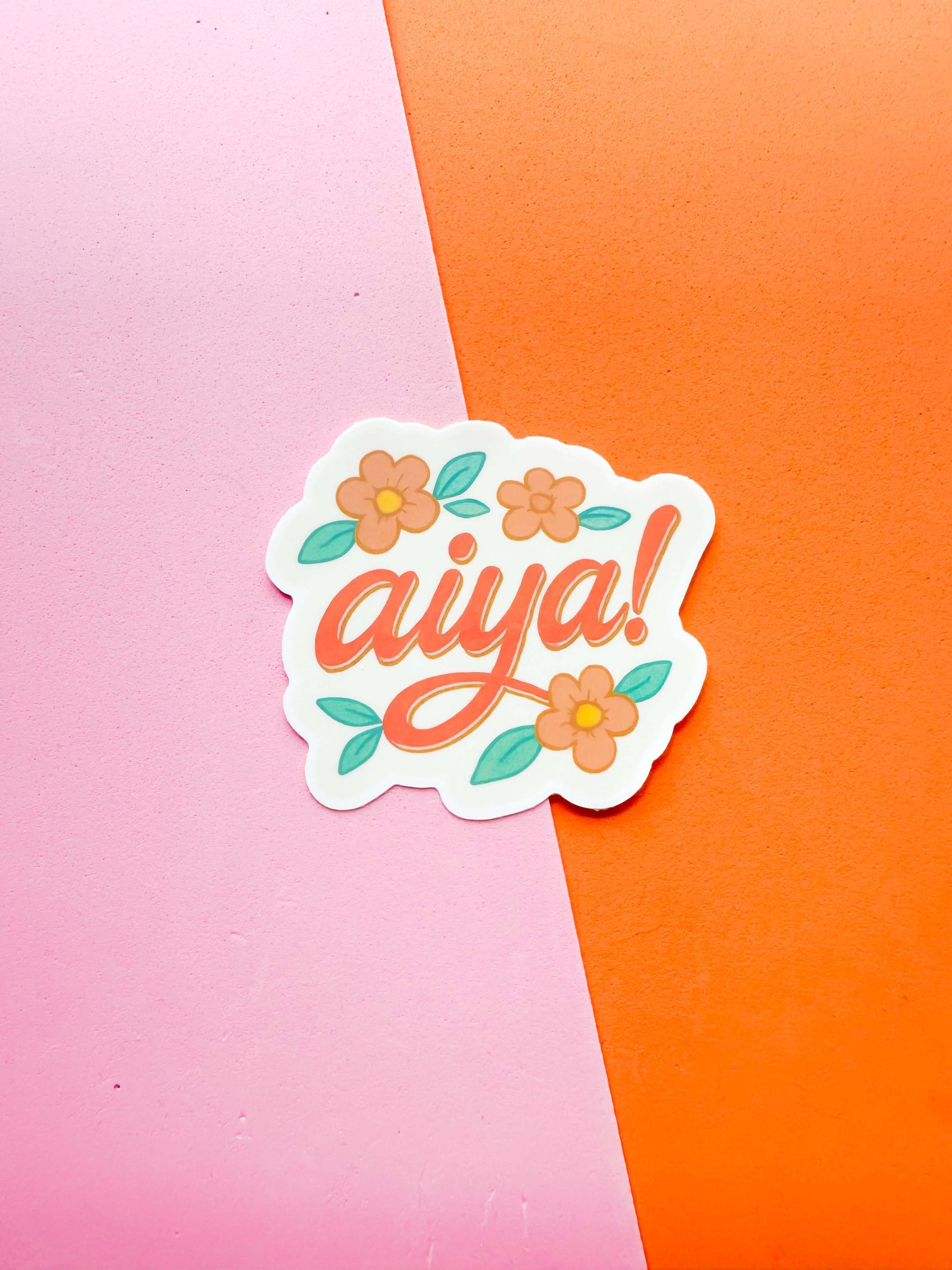 A matte premium vinyl sticker with the word 'aiya' written in stylized lettering, surrounded by floral designs