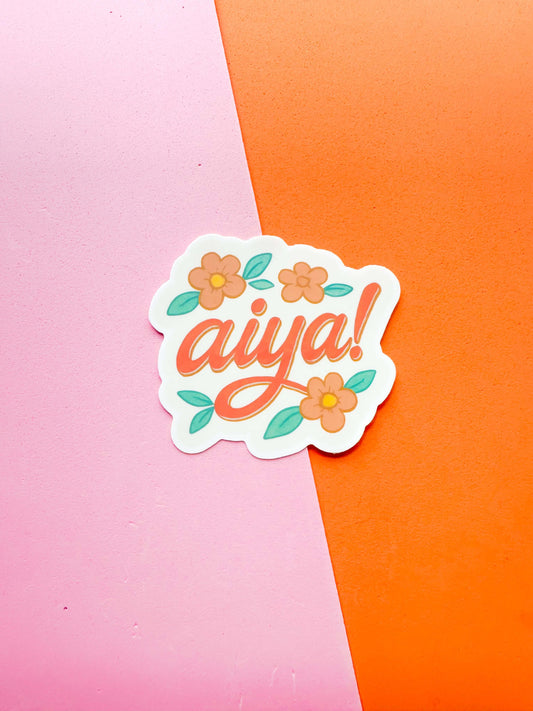 A matte premium vinyl sticker with the word 'aiya' written in stylized lettering, surrounded by floral designs