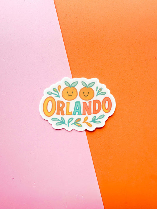 A matte premium vinyl sticker with the word 'ORLANDO' written in a stylized font, surrounded by a drawing of orange fruits 