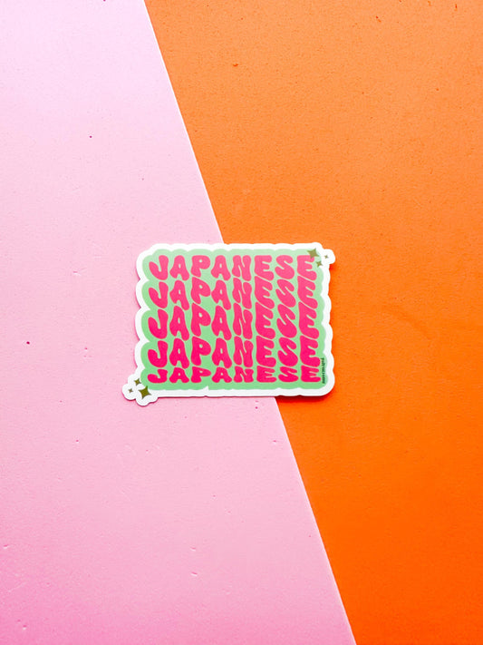 A vinyl sticker with Japanese text in pink on a green background 