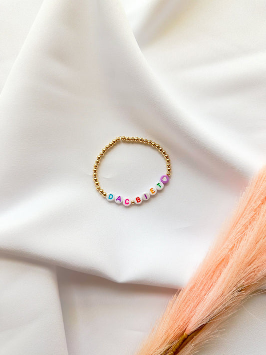 A gold-filled beaded bracelet with the phrase 'DAC BIET'  