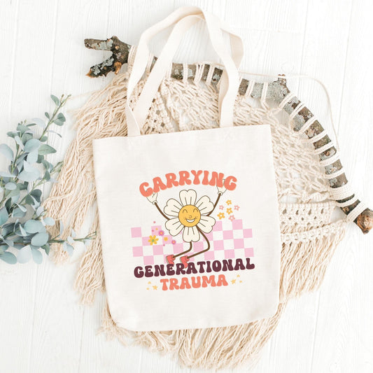 Canvas tote bag with the text 'Carrying Generational Trauma' printed on the front, featuring a flower illustration, displayed on a neutral background with decorative elements.
