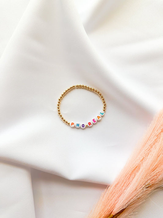 A gold-filled beaded bracelet with the phrase 'PHO REAL' 