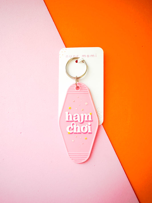 Pink keychain with 'hajn choi' text on a white card against a pink and orange background